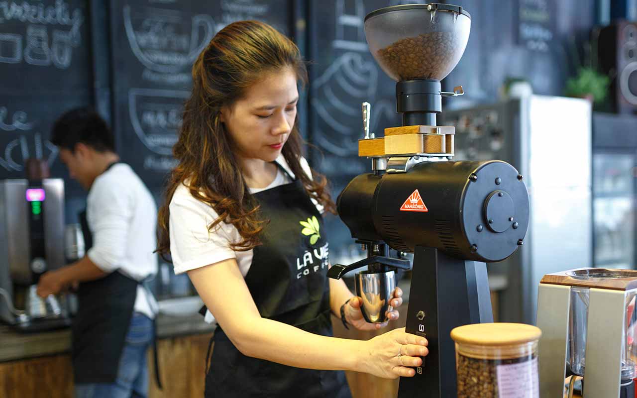 یک باریستا مشغول به اسیاب قهوه